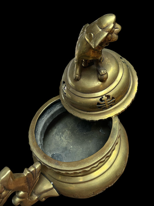 Brass incense burner with a lion design on a black background